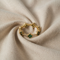 Anni – Gold Ring with Floral Decorations and Emerald Element.